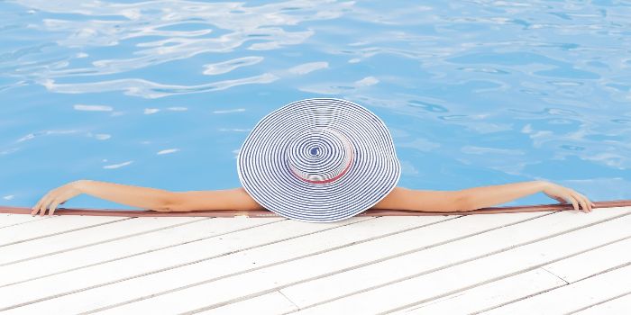 eine Frau mit einem Sonnenhut liegt im Pool