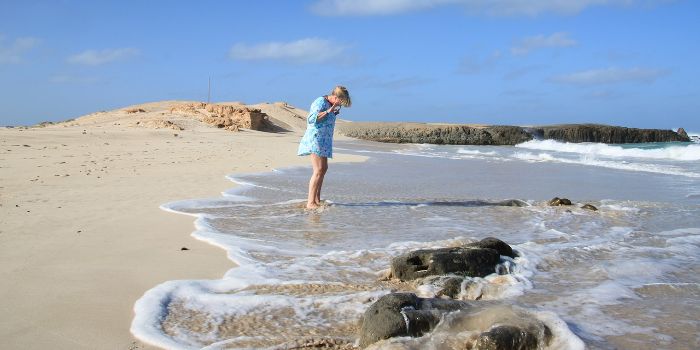 Eine Frau steht im Meer an einem Sandstrand in Kap Verde