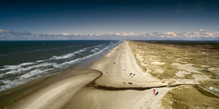 Das Bild zeigt einen langen Strandabschnitt an der Nordsee mit starkem Wellengang