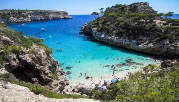 Eine Meeresbucht mit eimem schönen Sandstrand wo einige Touristen Baden