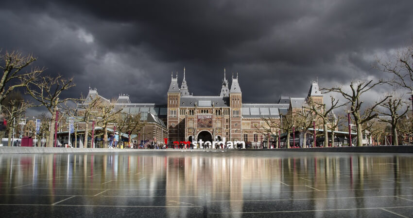 Das Rijksmuseum von außen fotografiert mit, wobei schwarze Gewitterwolken über das Museum ziehen.