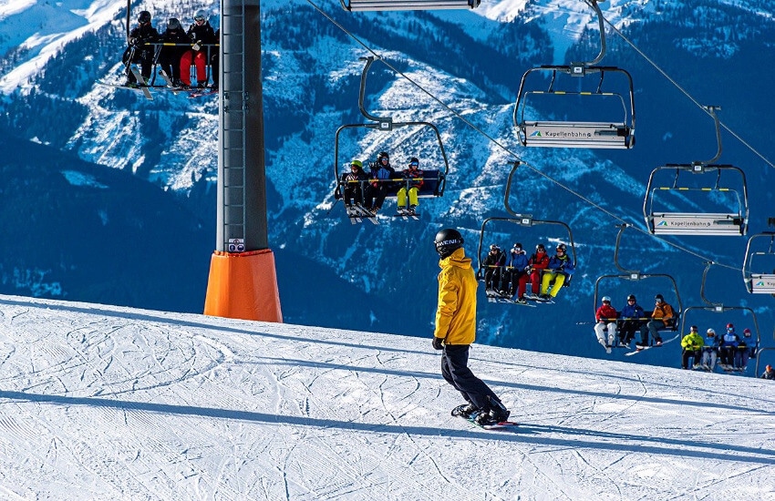 Ein Sessellift befördert Skifahrer bei schönstem Wetter auf dem Berg.