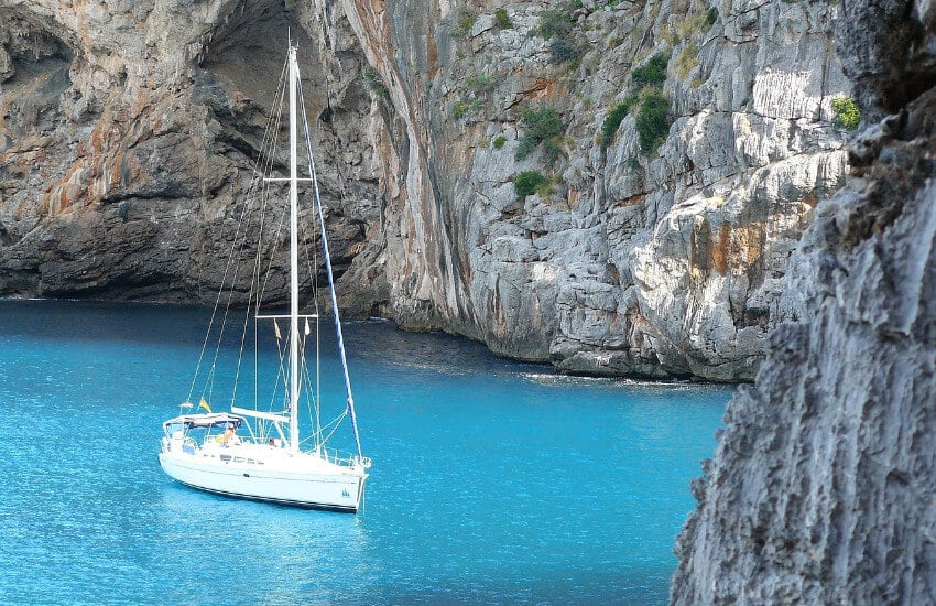 Ein Segelboot ankert im türkisen Meer zwischen steilen Steinwänden.