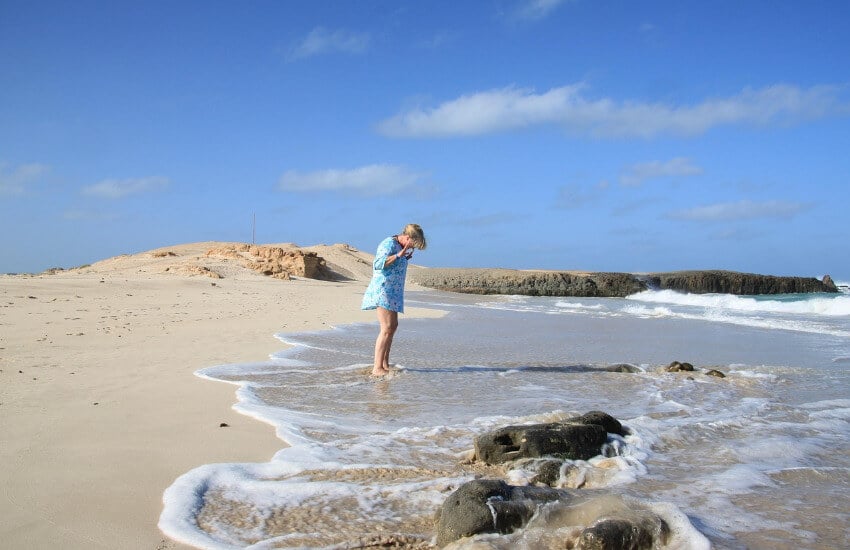 Eine Frau steht im Meer an einem Sandstrand in Kapverde