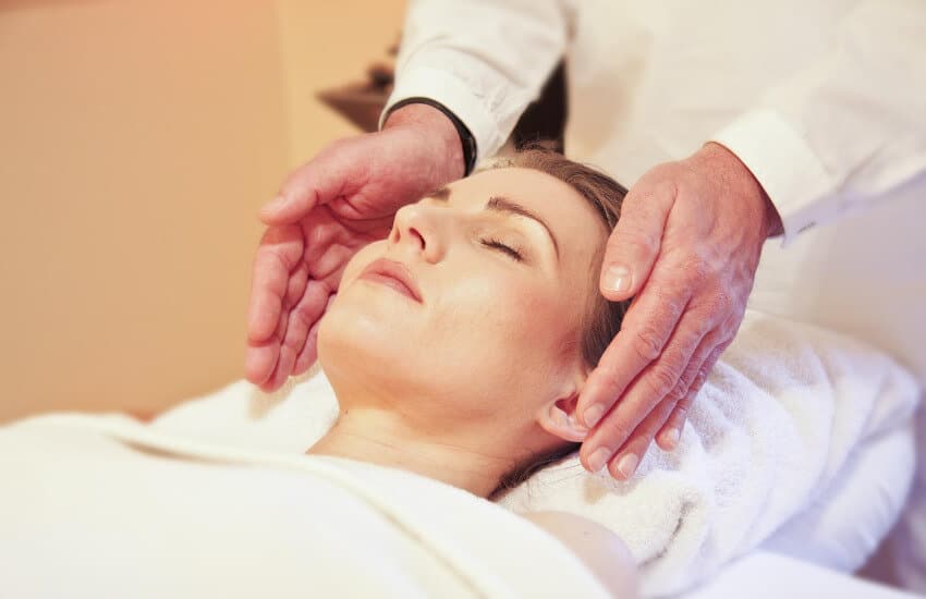 Eine Frau liegt auf einer Liege und genießt eine Wellnessbehandlung.